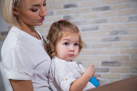 Caring mother with her kid daughter. Closeup shot of little toddler girl on womans knees holding toy.の写真素材