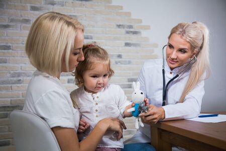 Professional medical pediatrician doctor in white uniform consult mother with her daughter. Pediatrist with kid patient good relationship trust conceptの写真素材