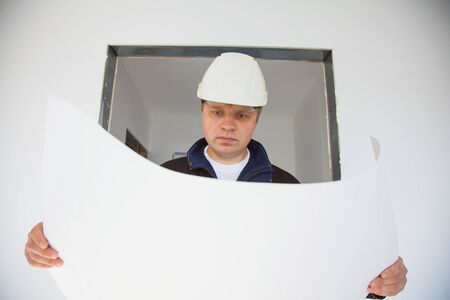Portrait of an architect builder studying layout plan of the rooms, engineer working on construction site, flat renovation, professional foreman at workの写真素材