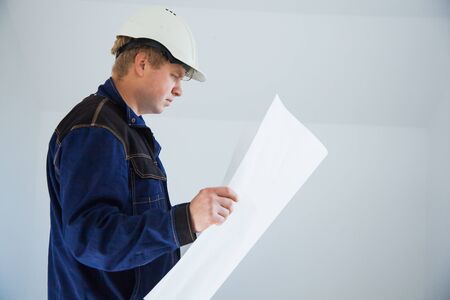 Portrait of an architect builder studying layout plan of the rooms, engineer working on construction site, flat renovation, professional foreman at workの写真素材