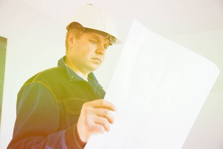 Portrait of an architect builder studying layout plan of the rooms, engineer working on construction site, flat renovation, professional foreman at workの写真素材
