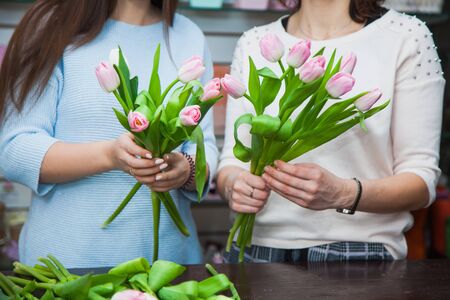 Two female florist designers making holiday tulip bouquets at flower shop. Floral decoration processの写真素材