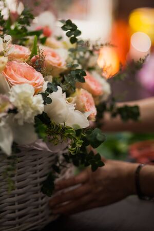 Vertical shot of beautiful fresh flowers bouquet designed in basket. Different types of blossoms at floristic studio.の写真素材