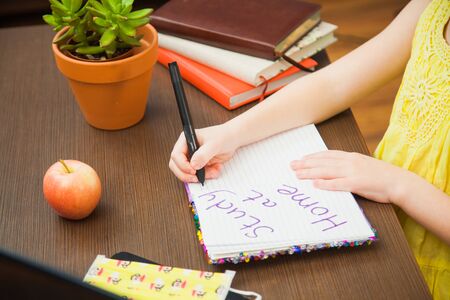 Closeup image child hands medical antiviral mask write in paper notebook study at home. Little elementary student ready for online lessons. Social distance, quarantine isolation concept.の写真素材