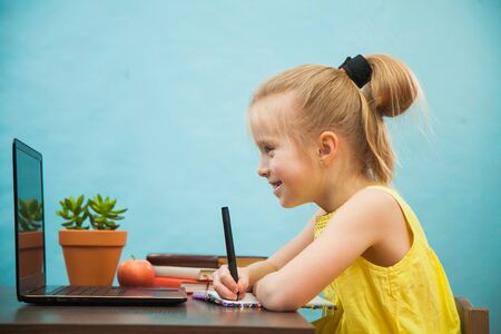 Happy preteen child learn lessons at home, homeschooling with laptop. Social distance during quarantine, self-isolation, online education conceptの写真素材
