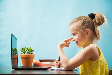 Happy preteen child learn lessons at home, homeschooling with laptop. Social distance during quarantine, self-isolation, online education conceptの写真素材