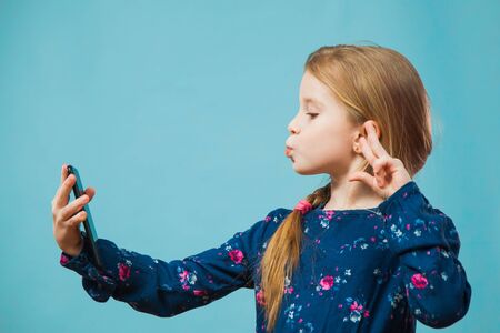 Preteen girl making selfie on smartphone. Little child model with modern phone photoshooting herself. Trend, young generation, social media, gadget concept.の写真素材