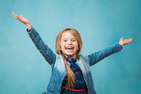 Happy delighted girl in denim jacket smile with hands up. Positive emotion, copy space for text, advertising concept.の写真素材