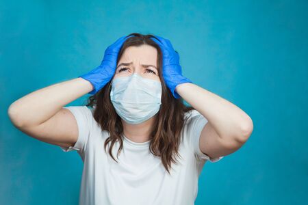 Young woman in antiviral medical mask and protective gloves feel depressed, sad and worried. Stress and fear on quarantine concept.の写真素材