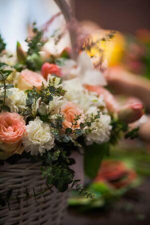 Vertical shot of beautiful fresh flowers bouquet designed in basket. Different types of blossoms at floristic studio.の写真素材