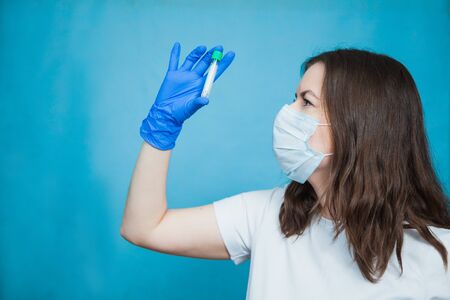 Medical student with empty blood test tube on blue background. Vaccine research, virus prevention concept.の写真素材