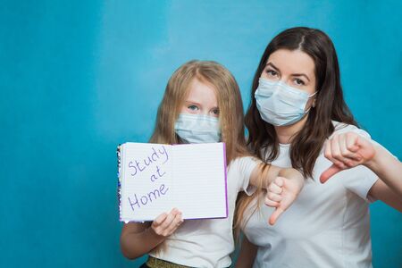 Unhappy mother and daughter show text study at home, hard time of homeschooling. Parents going mad and exhausted on quarantine with children. Home isolation concept. Thumbs down.の写真素材