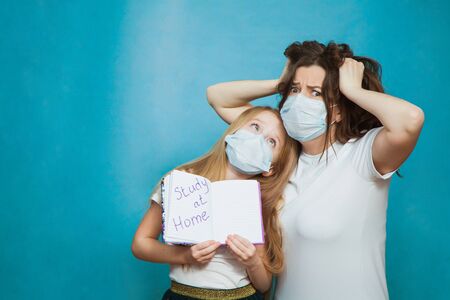 Mother and daughter show text study at home, hard time of homeschooling. Parents going mad and exhausted on quarantine with children. Home isolation concept.の写真素材