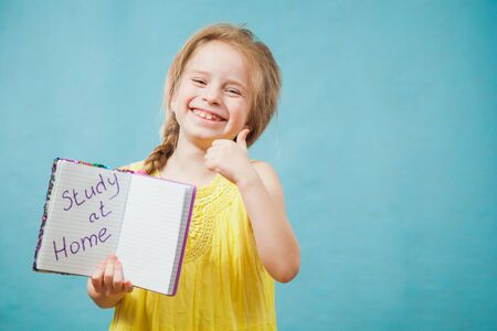 Happy delighted girl in yellow dress smile with written text study at home. Positive emotion, copy space for text, homeschooling, quarantine and social distancing concept.の写真素材