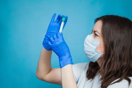 Medical student with empty blood test tube on blue background. Vaccine research, virus prevention concept.の写真素材