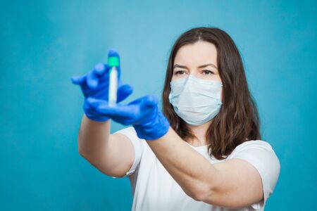 Medical student with empty blood test tube on blue background. Vaccine research, virus prevention concept.の写真素材