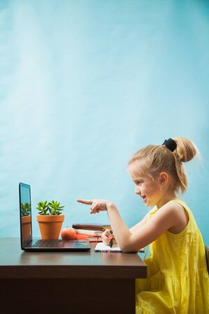 Happy preteen child learn lessons at home, homeschooling with laptop. Little girl enjoy using technologies. Social distance during quarantine, self-isolation, online education conceptの写真素材