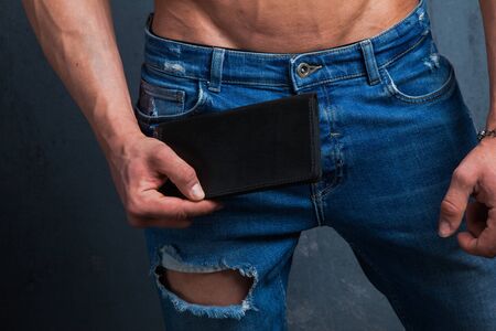 Closeup of male hand holding leather wallet. Man in jeans demonstrate his modern purse.の写真素材