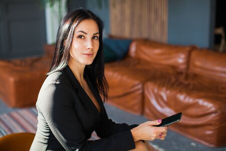 Beautiful sexy blogger using smartphone at home. Young business lady with mobile phone texting message, working from home.の写真素材