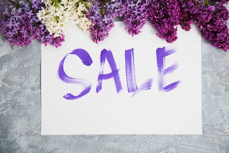 Handwritten word sale in white frame lay in lilac blossom. Shopping concept.の写真素材