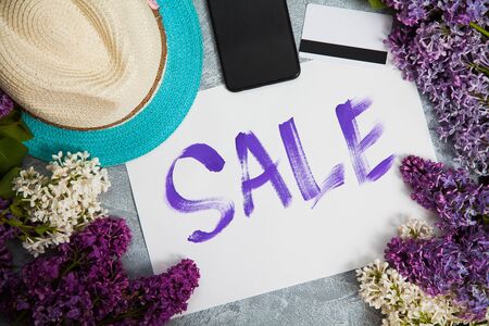 Handwritten word sale in white frame, smartphone, credit card lay in lilac blossom. Shopping concept.の写真素材