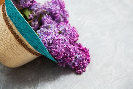 Beautiful purple lilac blossom into summer hat on grey background. Floral concept with copyspace for some text.の写真素材
