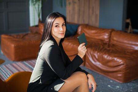 Beautiful sexy blogger using smartphone at home. Young business lady with mobile phone texting message, working from home.の写真素材