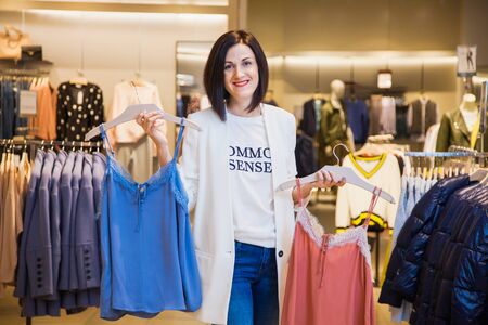 Young woman in clothes store choosing outfit. Female person in shopping mall, shopping stylist at work.の写真素材