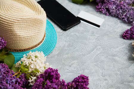 Summer hat, smartphone, credit card and lilac blossom on grey background. Spring shopping concept, copy space for text.の写真素材