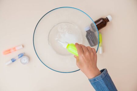 Making slime, step by step instruction, step five, adding thickening agent. Childs hands preparing homemade toy.の写真素材