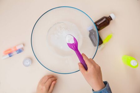 Making slime, step by step instruction, step two, adding soda. Childs hands preparing homemade toy.の写真素材