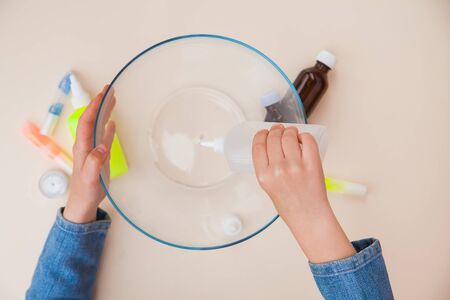 Making slime, step by step instruction, step one, adding stationery glue. Childs hands preparing homemade toy.の写真素材