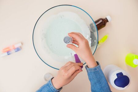 Making slime, step by step instruction, step six, adding glitter. Child's hands preparing homemade toy.の写真素材
