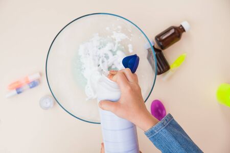 Making slime, step by step instruction, step four, adding shaving foam. Childs hands preparing homemade toy.の写真素材