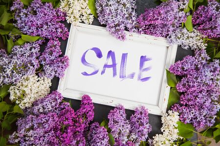 Spring shopping sale concept, handwritten word sale and lilac flowers on table. Floral arrangement with purple fresh blossoms.の写真素材