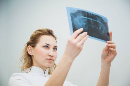 Female doctor dentist examining x-ray of human jaw. Professional stomatologist checking dental x-ray image at clinic office.の写真素材