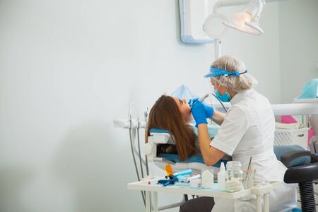 Female dentist curing teeth cavity in blue gloves and protective mask. Dentist caries treatment at dental clinic office. People, medicine, stomatology and health care concept. Cope spaceの写真素材