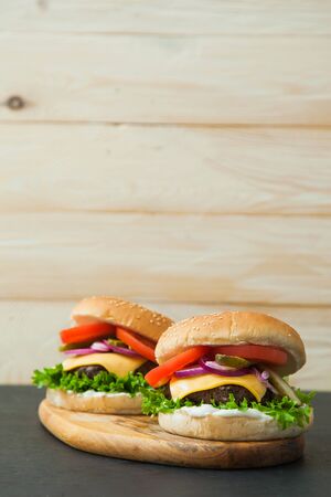 Delicious classic burgers on wooden serving board. Fast food, junk eating concept.の写真素材