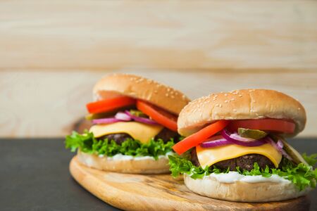Delicious classic burgers on wooden serving board. Fast food, junk eating concept.の写真素材