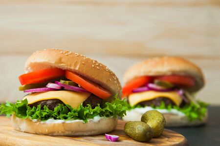 Delicious classic burgers on wooden serving board. Fast food, junk eating concept.の写真素材
