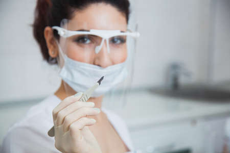 Female stomatologist ready for dental surgery, holding scalpel. Toothcare concept. Dentist at clinic office. Toothcare conceptの写真素材