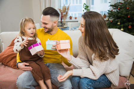 Mom and dad unboxing gift for little daughter at home on Christmas time. Family together celebrate New year.の写真素材