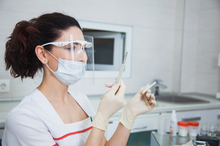 Female stomatologist ready for dental surgery, holding scalpel. Toothcare concept. Dentist at clinic office. Toothcare conceptの写真素材