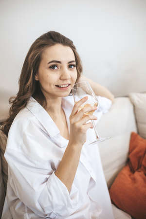 Young woman with glass of wine at home. Female person relax drinking wine.の写真素材