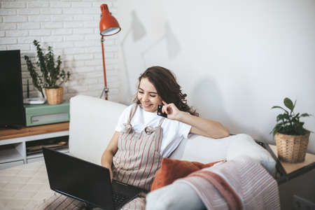 Young millennial woman shopping online at home. Female person using laptop and credit card to buy new things.の写真素材