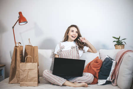Young millennial woman shopping online at home.の写真素材