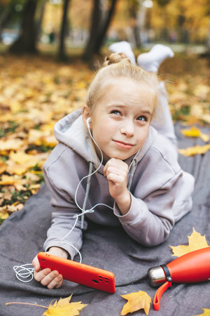 Gen z teenage girl using smartphote outdoors in autumn time.の写真素材