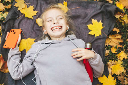 Gen z teenage girl using smartphote outdoors in autumn time.の写真素材