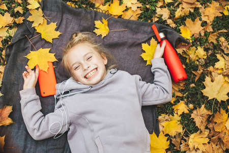 Gen z teenage girl using smartphote outdoors in autumn time.の写真素材