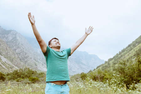 Happy man in natural mountain area raise hands.の写真素材